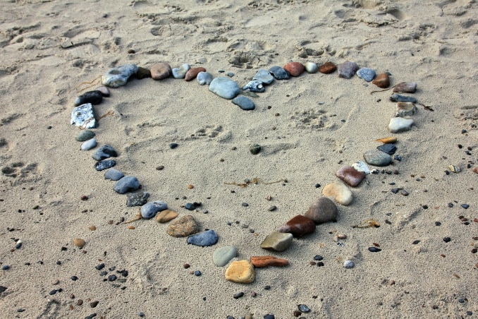 Das Foto zeigt ein Herz im Sand